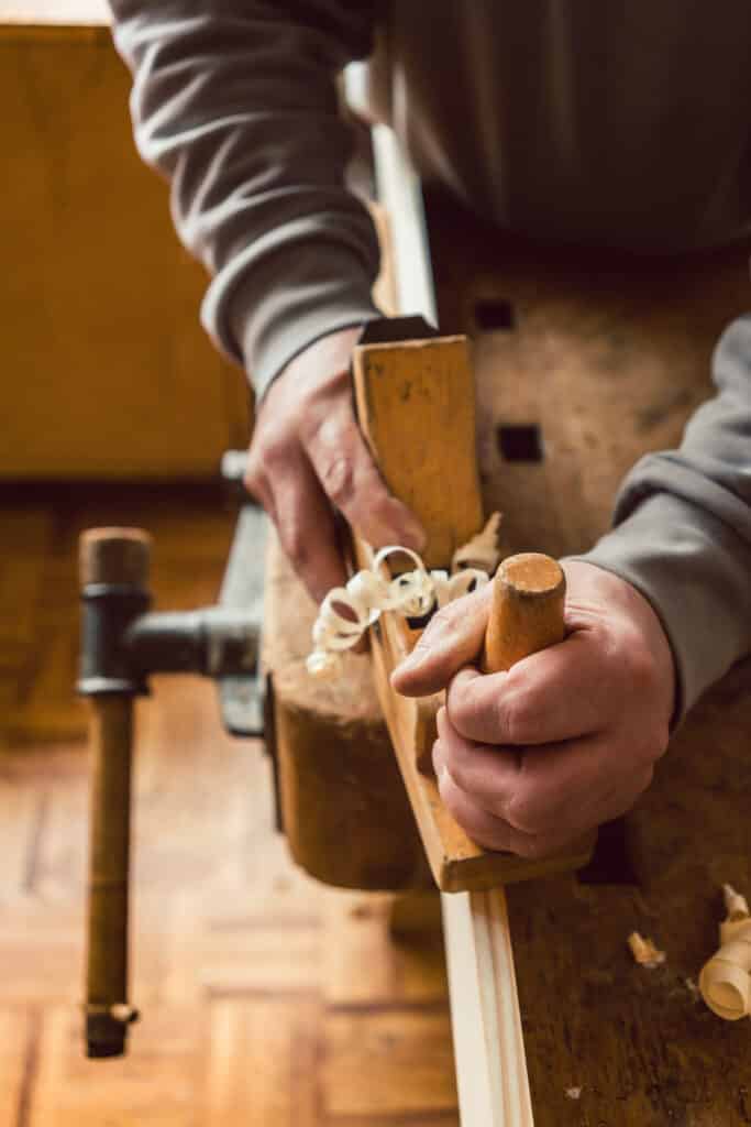 Top view of carpenter hand working with wood planer