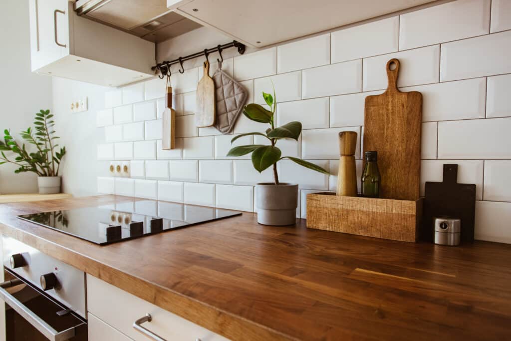 Cuisine Bois Moderne, Carrelage Métro Blanc et Déco Plan de travail bois foncé cuisine moderne avec plaque vitrocéramique, carreaux métro blancs et ustensiles suspendus.