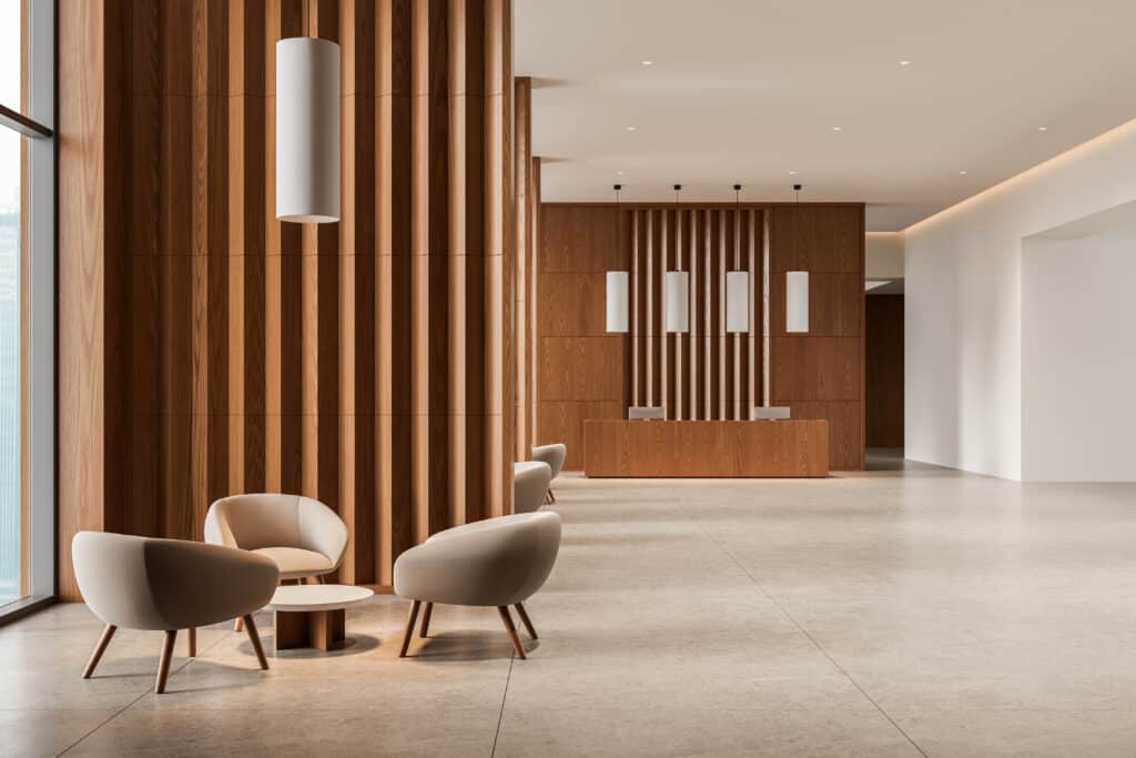 Hall d'accueil design bois : mobilier moderne et réception Hall d'accueil moderne avec mur en bois à lattes verticales, comptoir d'accueil en bois et fauteuils d'attente beiges près d'une fenêtre.