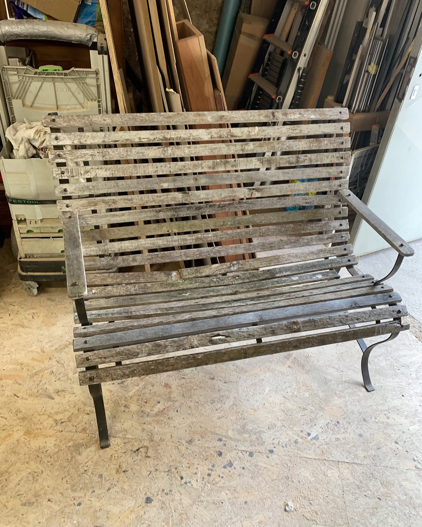 Banc de jardin vintage en bois vieilli et métal, style rustique dans un atelier.
