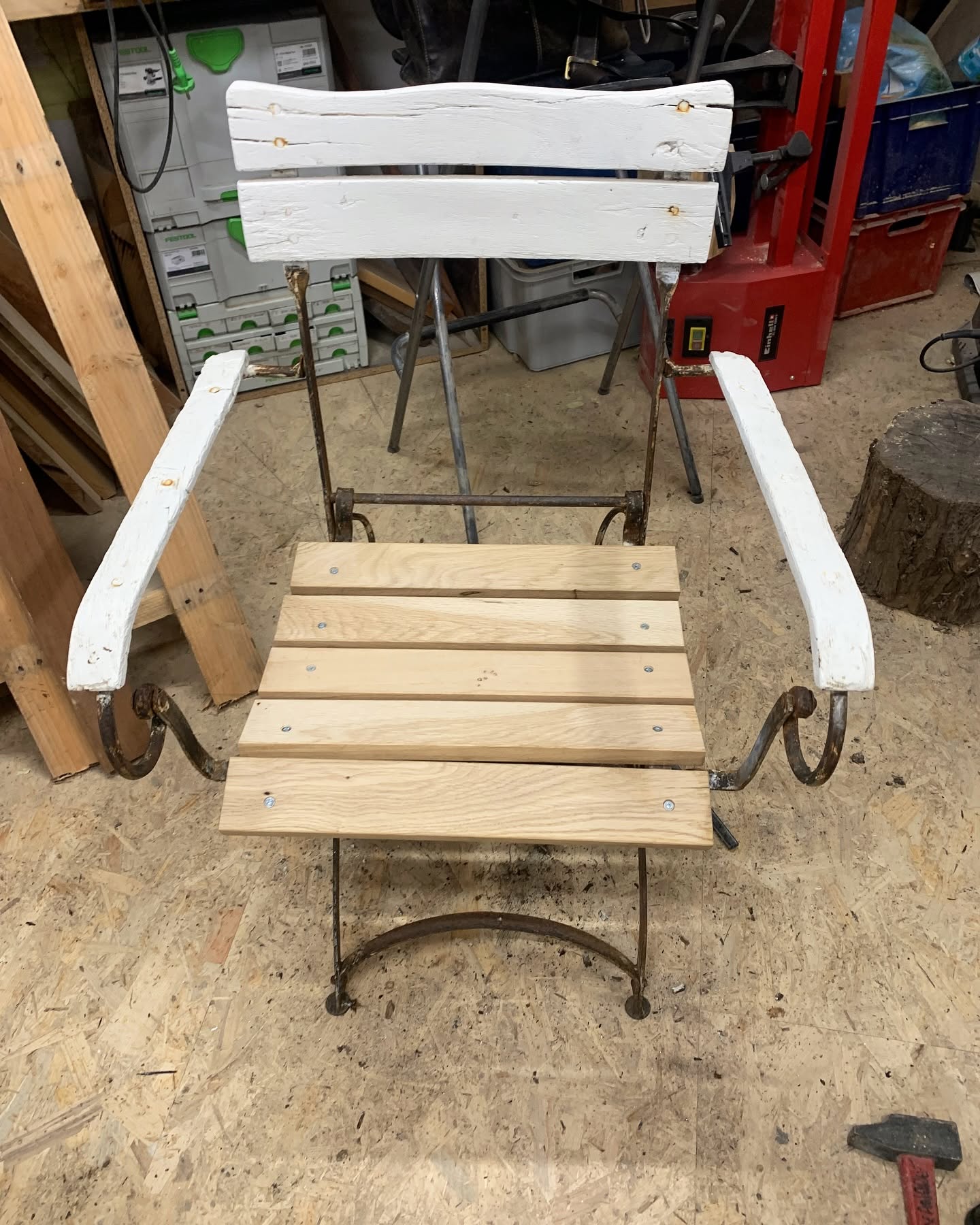 Chaise pliante vintage en bois et fer forgé en cours de restauration dans un atelier.