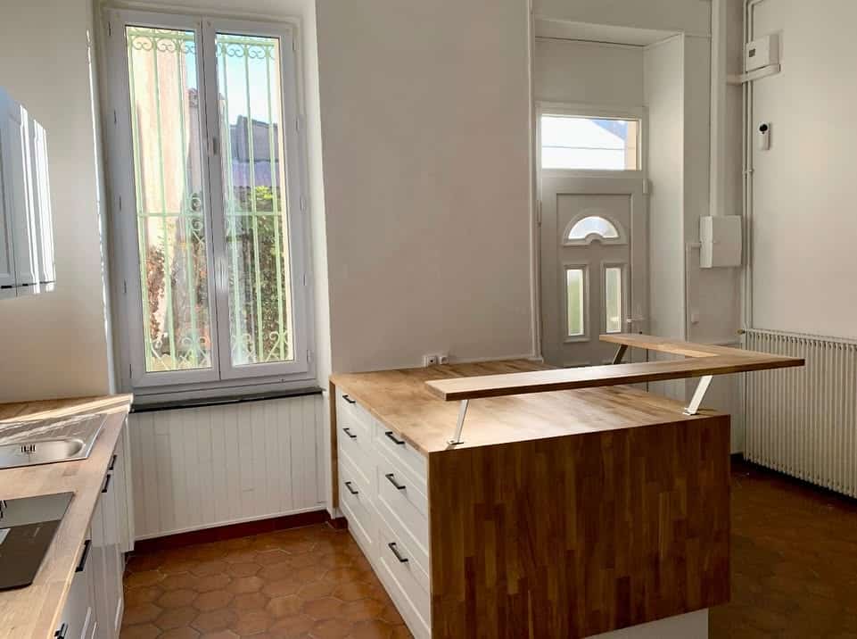 Cuisine moderne avec îlot en bois massif, meubles blancs et sol en tomettes.