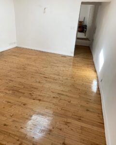 Parquet en chêne clair brillant dans une pièce vide lumineuse aux murs blancs.